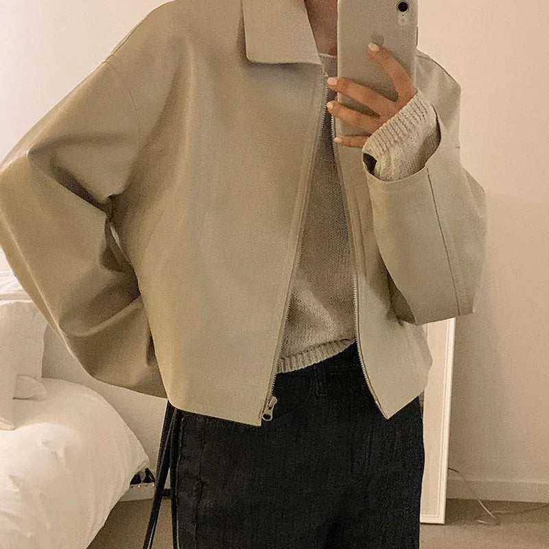 Oversized beige faux leather jacket with wide sleeves and relaxed fit, styled with casual sweater.