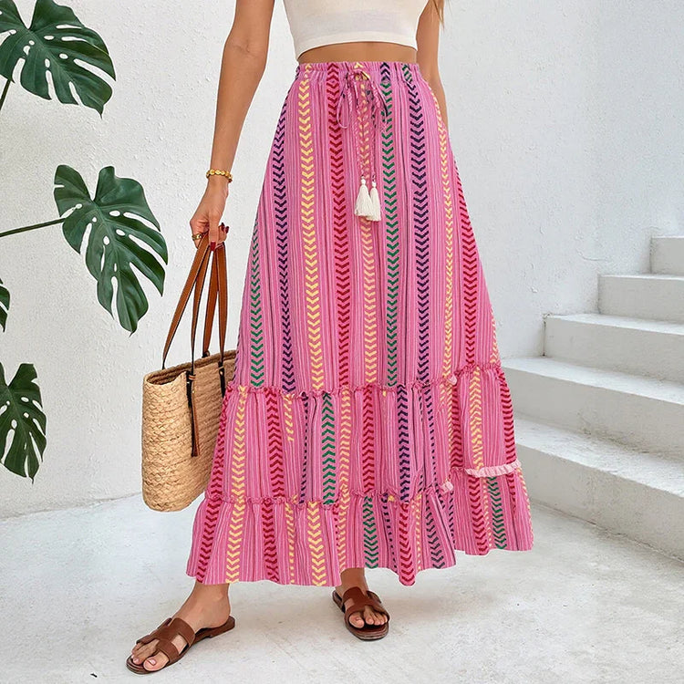 Woman wearing a pink boho maxi skirt with chevron print, flowy fit, paired with a white crop top.