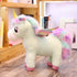 Plush pastel unicorn toy with rainbow mane, wings, and pink hooves on wood floor