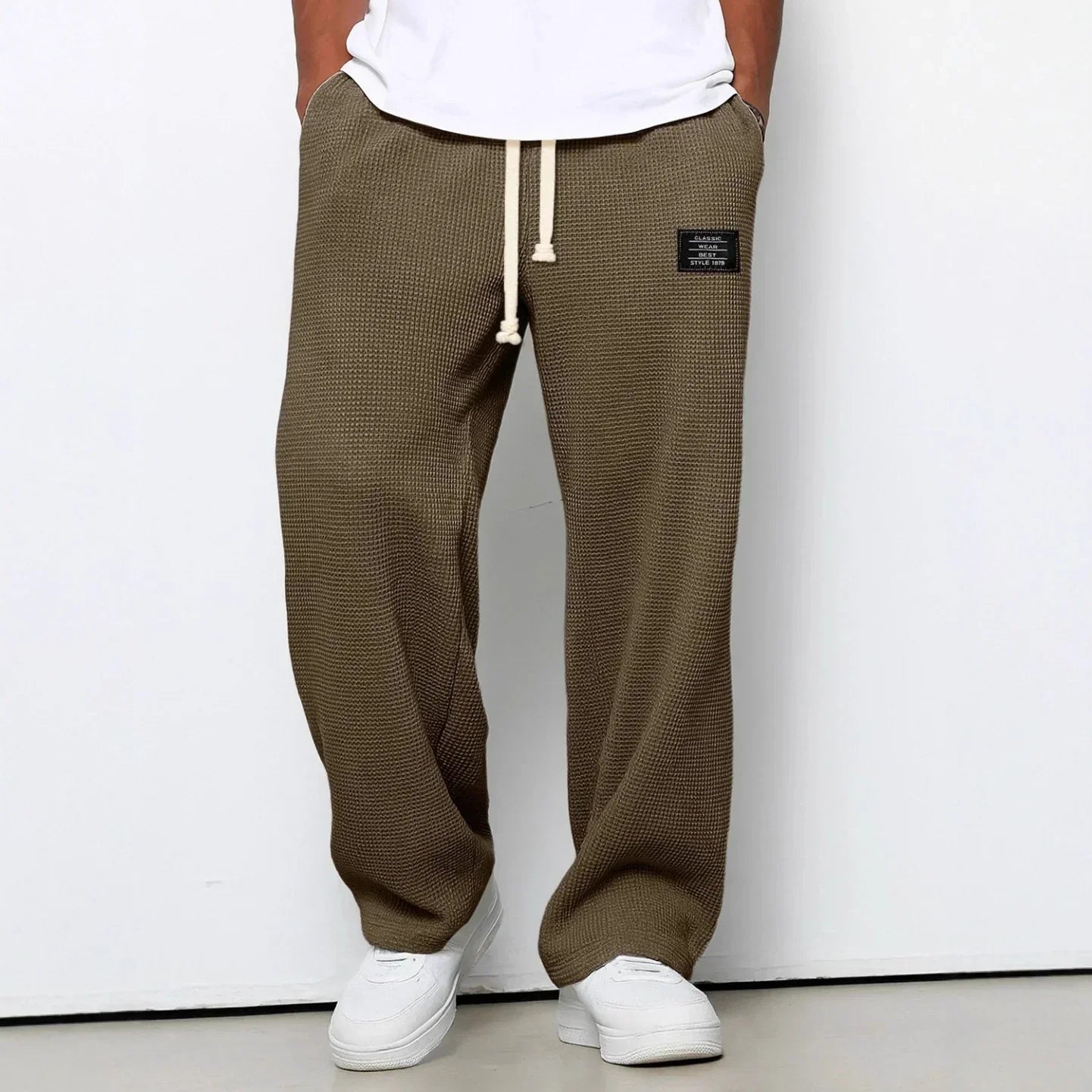 Man wearing loose fit olive waffle knit pants with drawstring waist and patch detail