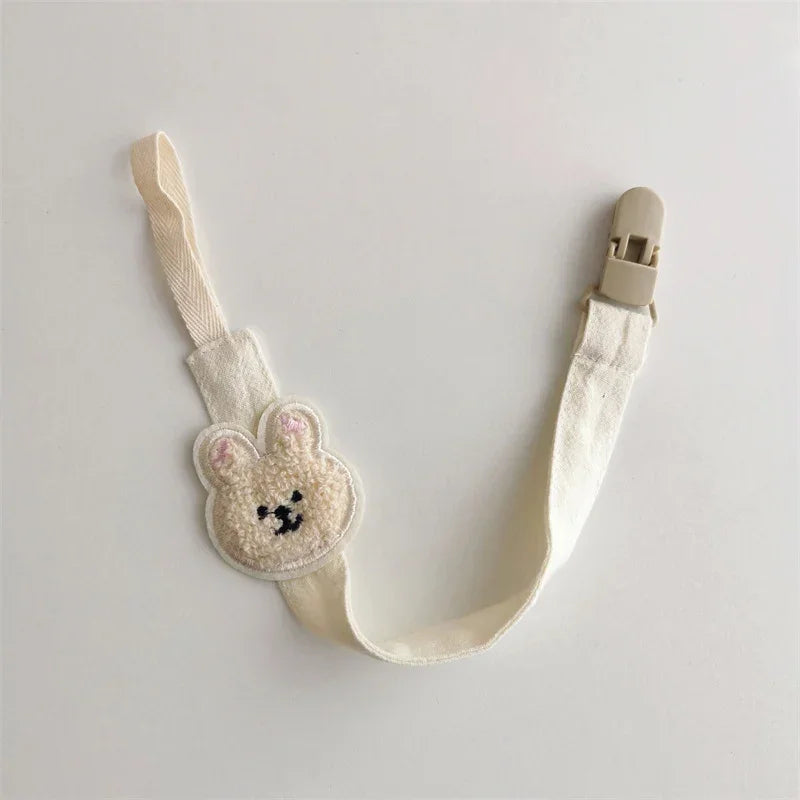 Beige fabric strap with cute bear face patch and plastic clip, soft textured accessory