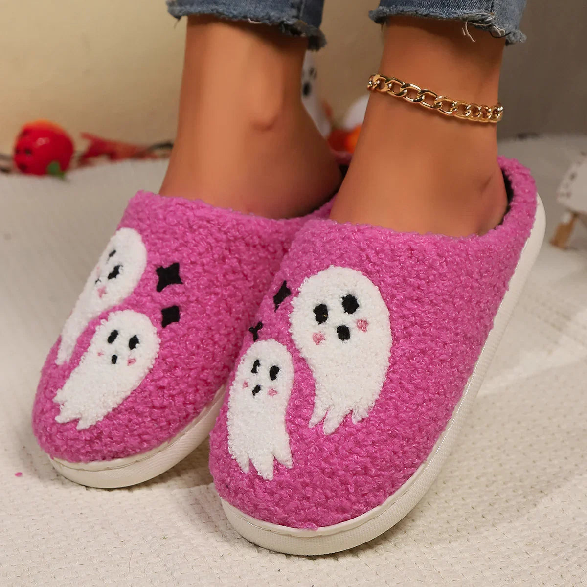 Pink fluffy slippers with white ghost pattern, cozy fit, worn with jeans.