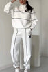 Woman wearing a white relaxed-fit tracksuit with black piping and M logo, sporty streetwear