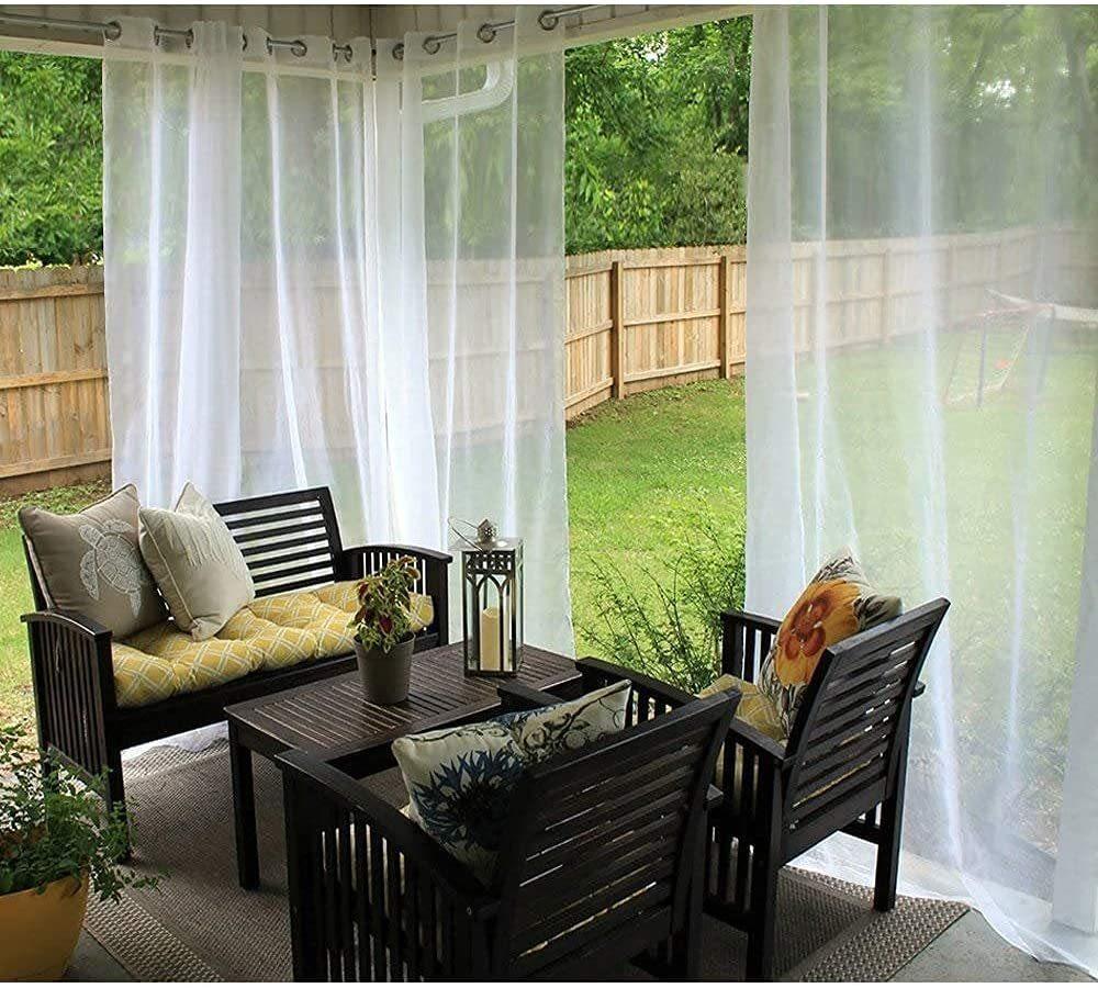 Outdoor patio with sheer white curtains, dark wood furniture, and colorful cushions