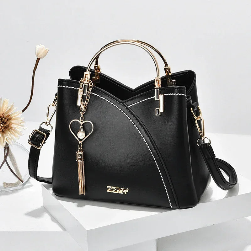 Black faux leather handbag with gold hardware, white stitching, structured fit, and detachable strap