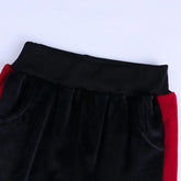 Black velvet joggers with red side panels, elastic waistband, relaxed fit streetwear