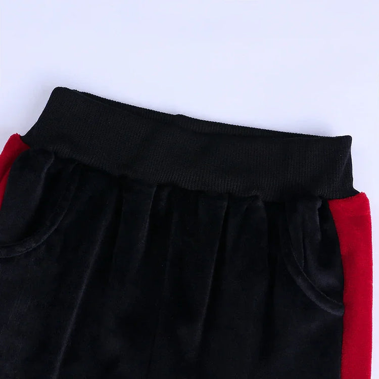 Black velvet joggers with red side panels, elastic waistband, relaxed fit streetwear