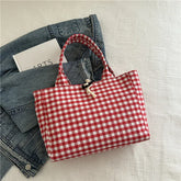 Red and white gingham tote bag with cotton rope closure, laid on a denim jacket