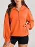 Woman wearing an oversized orange zip hoodie with kangaroo pocket and black biker shorts