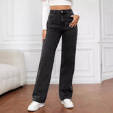Woman wearing high-waisted black wide-leg jeans, white crop top, and sneakers indoors.