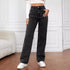 Woman wearing high-waisted black wide-leg jeans, white crop top, and sneakers indoors.