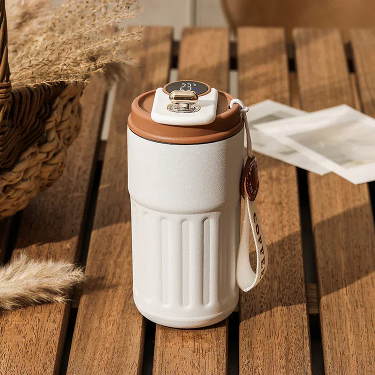 White and brown insulated travel mug with digital lid, modern design, on wooden table