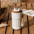 Modern white and brown insulated travel mug with digital lid, textured grip, on wooden table