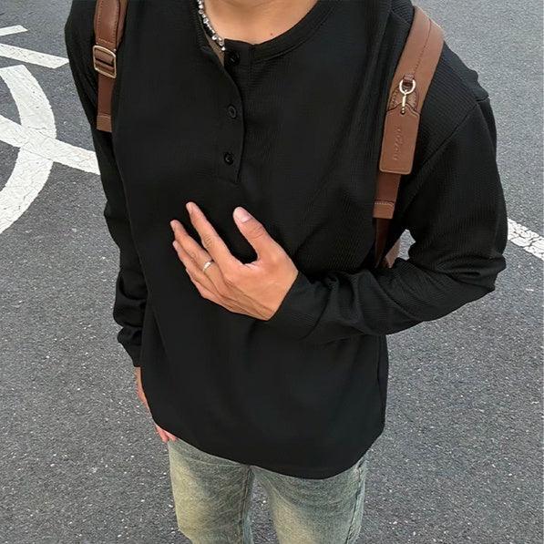 Man wearing black long-sleeve waffle knit henley shirt, slim fit, styled with jeans.