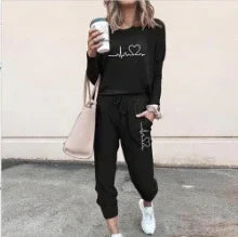 Woman in black streetwear lounge set with heart graphic, relaxed fit joggers, and white sneakers