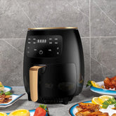 Sleek black digital air fryer with gold accents on kitchen counter, surrounded by plates of food.