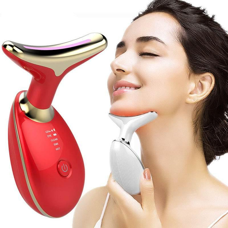 Woman using a metallic face massage device with red and gold trim on her jawline