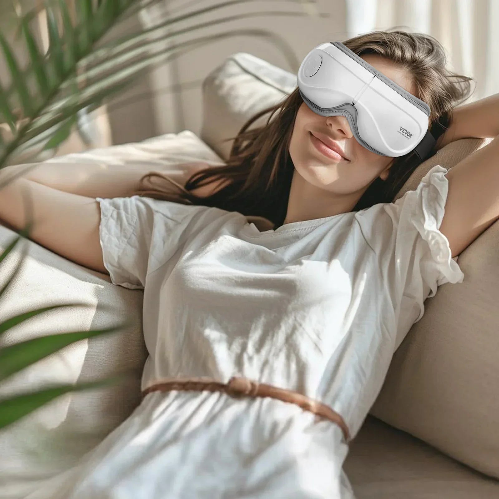 Woman wearing relaxed fit white cotton t-shirt dress, lounging with tech eye mask