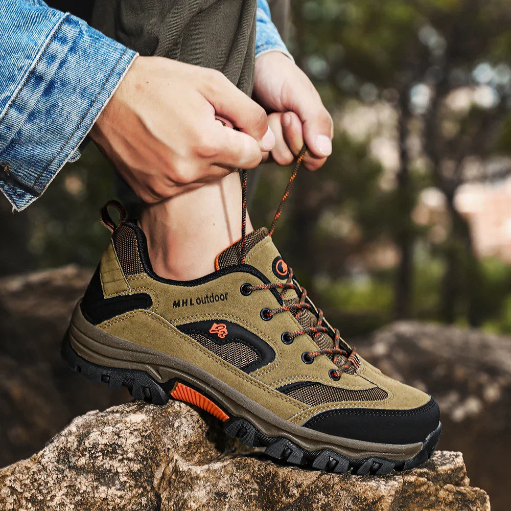Man tying olive green and black outdoor hiking shoe with rugged sole, suede and mesh material