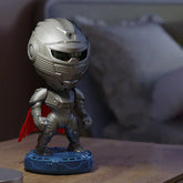 Futuristic silver armored figure with a red cape standing on a blue base