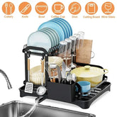 Black multi-tier dish drying rack with plates, bowls, cutlery, utensils, and glasses organized neatly.