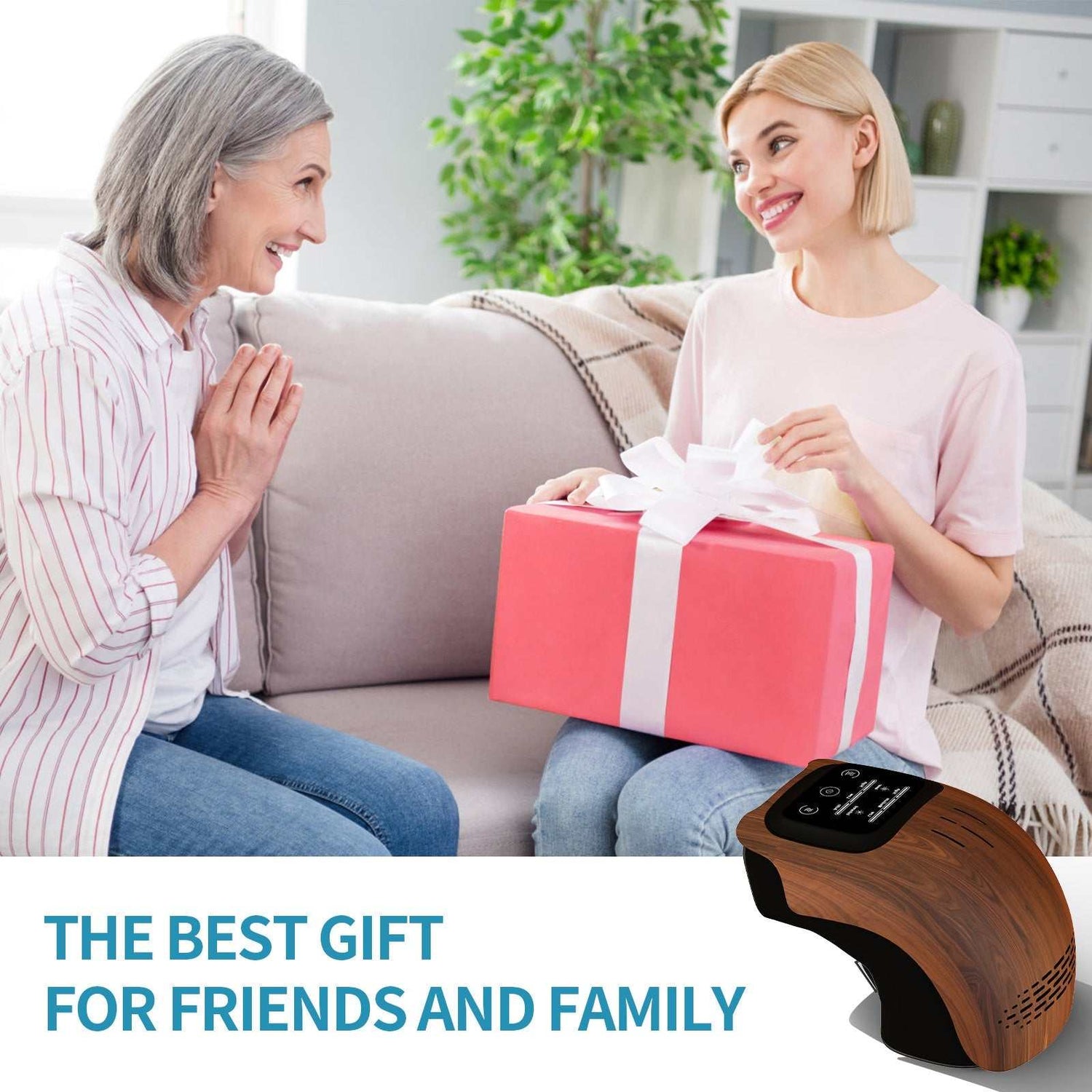 Two women in casual pastel tops and jeans exchanging a pink gift box on a beige sofa.