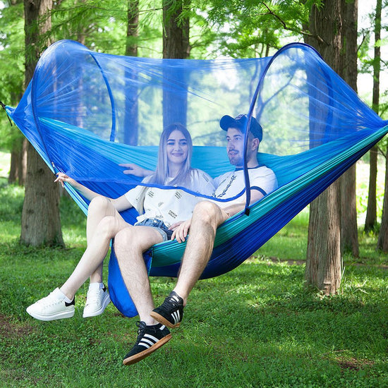 Couple relaxing in fully automatic quick opening hammock with mosquito net in forest