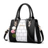 Black and white faux leather handbag with geometric panel design and pom pom keychain