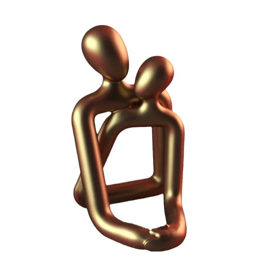 Abstract gold metallic sculpture of two embracing figures on white background