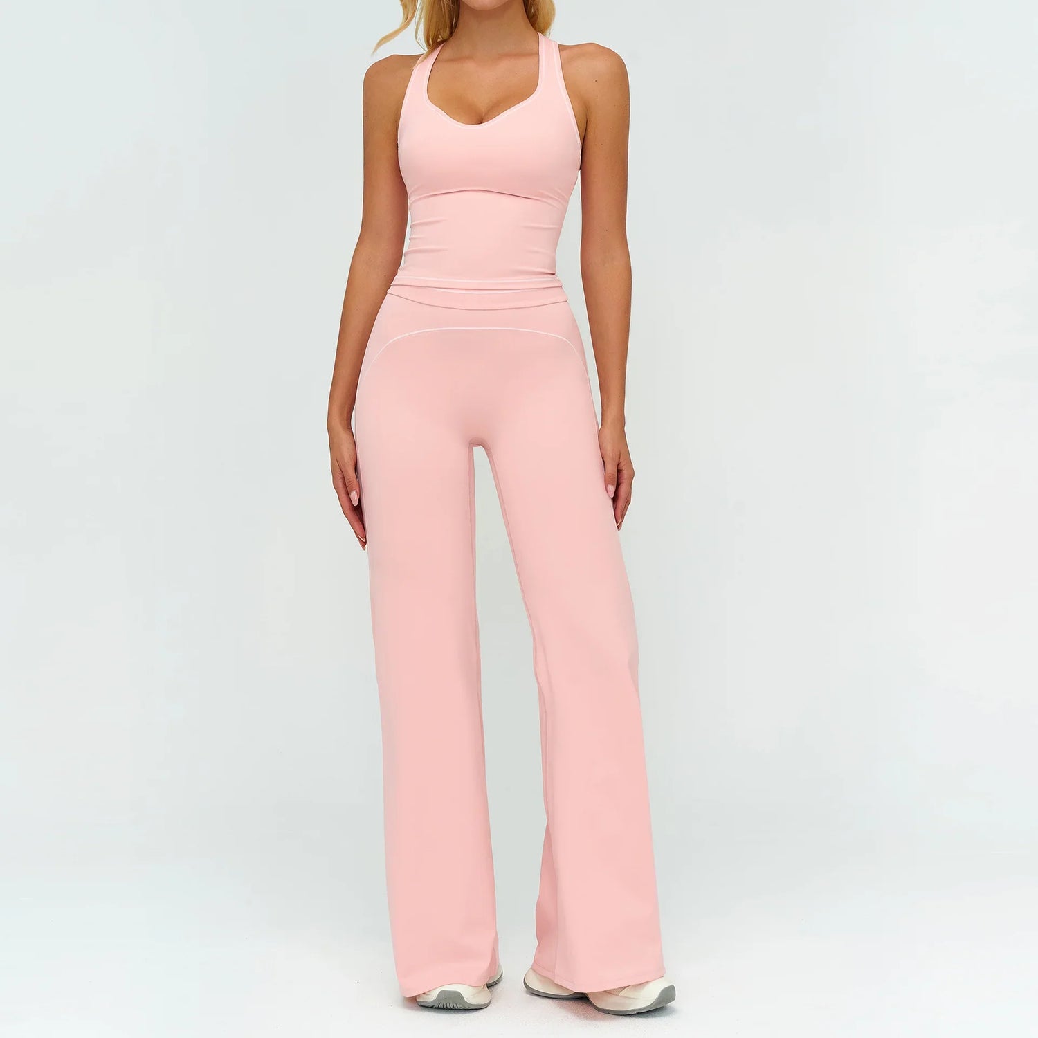 Woman wearing light pink fitted tank top and wide-leg pants, stretchy activewear set