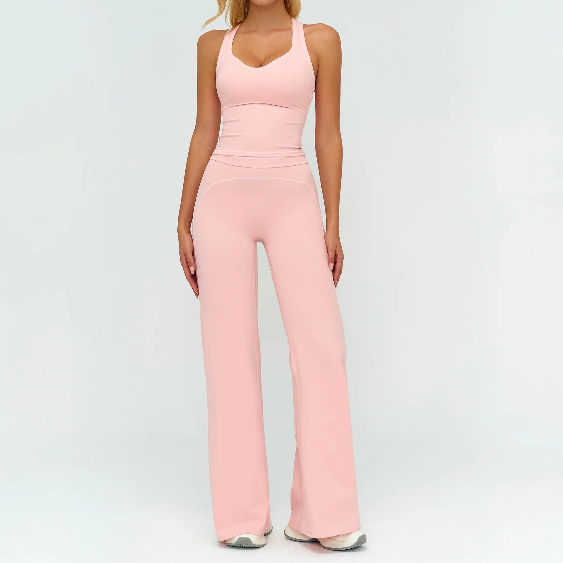 Woman wearing light pink fitted tank top and wide-leg pants, stretchy activewear set