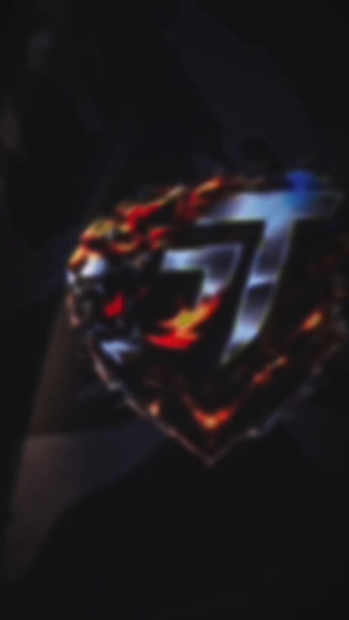 Blurry image of a black box with a fiery tiger graphic and a large metallic number 7, likely a gaming or collectible item, on a dark background.