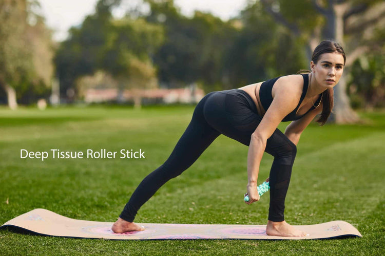 Woman in black athletic leggings and sports bra stretching on a yoga mat outdoors