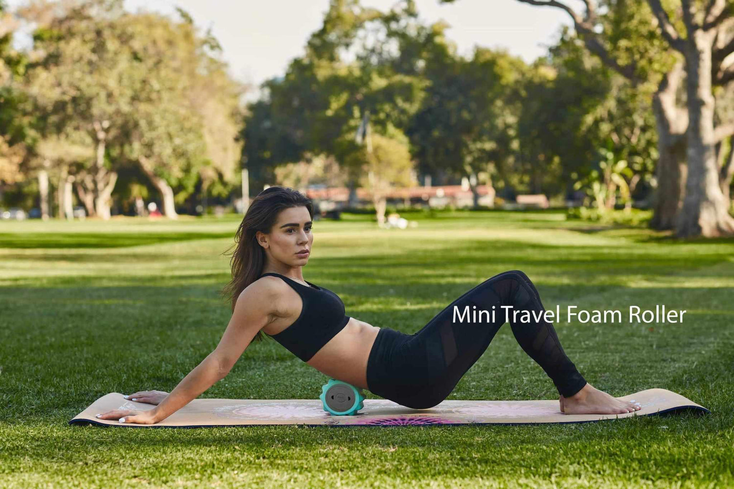 Woman in black athletic crop top and leggings, fitted and stretchy, exercising on yoga mat outdoors