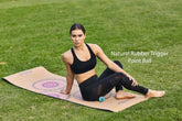 Woman in black athletic crop top and mesh leggings stretching on a yoga mat outdoors