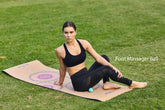 Woman in black sports bra and mesh panel leggings, sitting on yoga mat outdoors