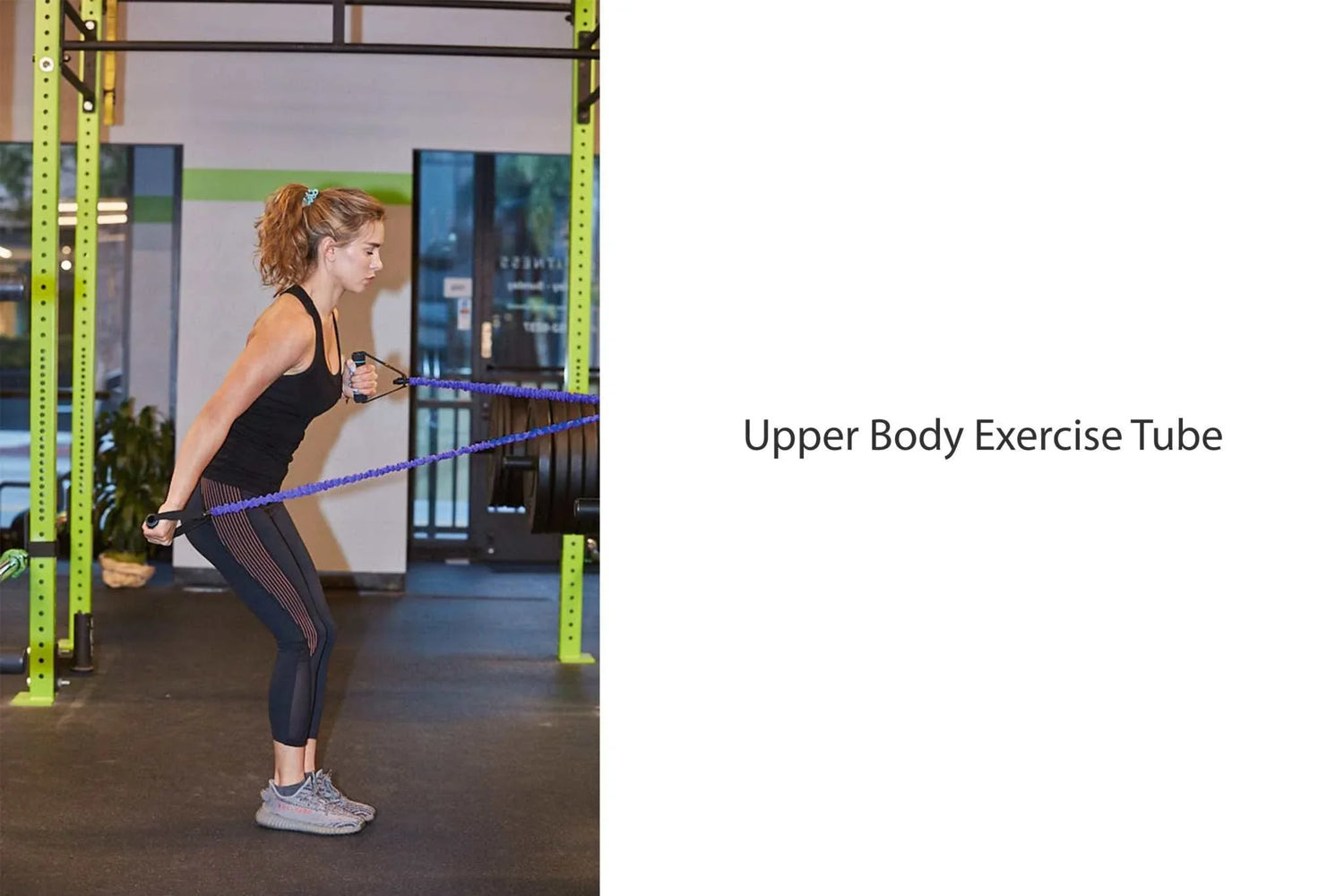 Woman in black fitted athletic tank top and striped leggings using resistance band for upper body workout